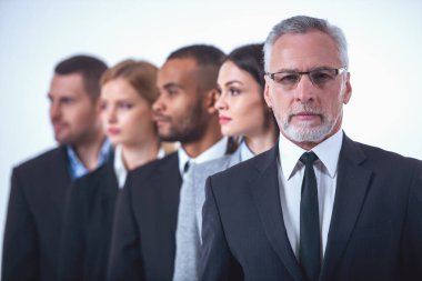 Güzel iş adamları takım elbiseli bir bekliyoruz bir tarafından kamera, beyaz izole ön planda yakışıklı olgun işadamı bakıyor