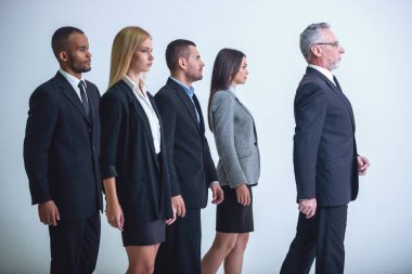 Güzel iş takım onların yakışıklı olgun patron, gri bir arka plan üzerinde arkasında duruyor