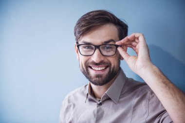 Kameraya bakarak ve ofiste çalışırken gülümseyen gözlük yakışıklı işadamı portresi