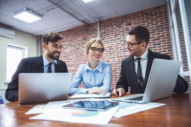 Dizüstü bilgisayarlar, belgeleri eğitim, söz ve ofiste çalışırken gülümseyen güzel iş adamları kullanarak