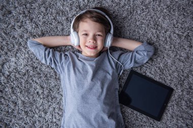 Küçük çocuk müzik, evde yerde yatarken süre gülümseyen ve kameraya bakarak Kulaklığımda Üstten Görünüm