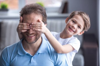 Baba ve oğul birlikte vakit ise gülümsüyorsun. Küçük çocuk baba gözleri koruyor