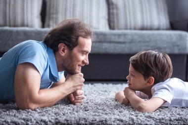 Yakışıklı baba ve birbirine bakarak ve birlikte evde vakit ise gülümseyen sevimli oğlu yan görünüm