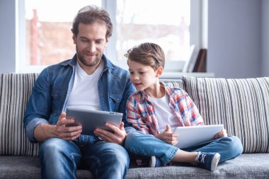 Baba ve oğul dijital tablet kullanarak ve birlikte evde vakit ise gülümseyen