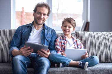 Baba ve oğul dijital tablet kullanarak ve birlikte evde vakit ise gülümseyen