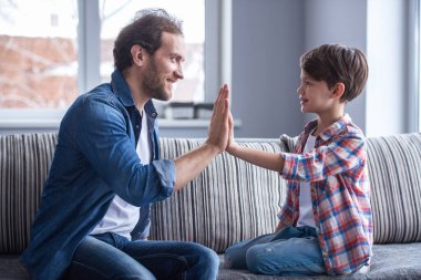Baba ve oğul yüksek beş veren ve birlikte evde vakit ise gülümseyen