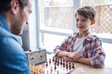 Baba ve oğul satranç oynamayı ve birlikte evde vakit ise gülümseyen