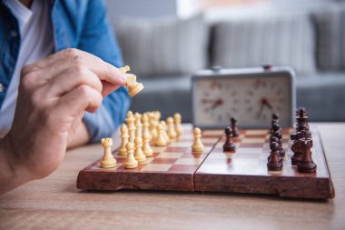 Satranç oynarken satranç taşını tutan gencin kırpılmış görüntü