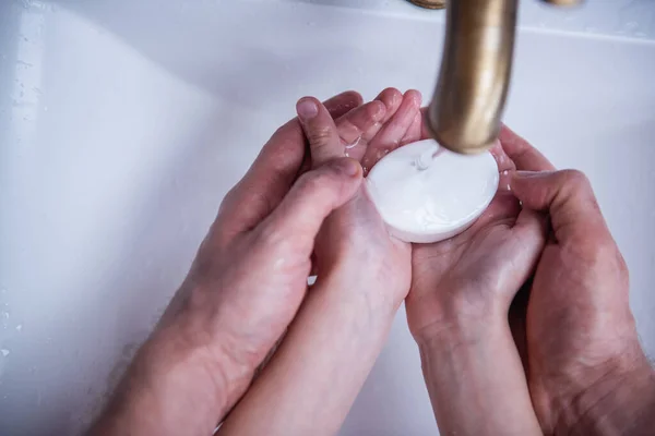 Cropped image of  little boy and his father washing hands with a soap in bathroom