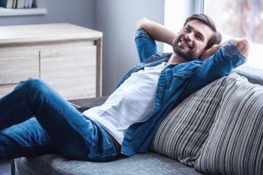 Evde kanepede otururken yakışıklı adam uzakta ve gülümseyen arıyor