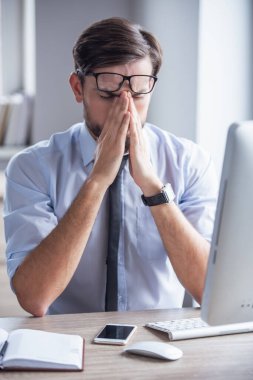 Yakışıklı yorgun işadamı gözlük tutan ve bir bilgisayar Office ile çalışırken burun köprüsü Masaj