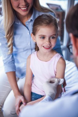 Güzel genç anne ve çocuk doktoru, küçük kızı. Doktor iğne yapıyor