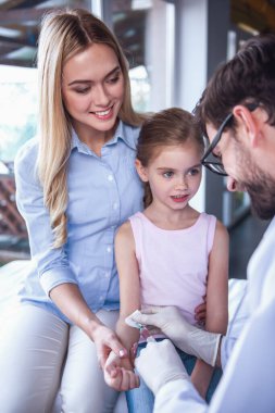 Güzel genç anne ve çocuk doktoru, küçük kızı. Doktor iğne yapıyor