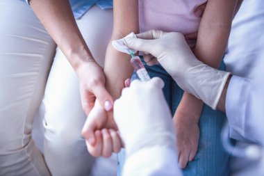 Güzel genç anne ve çocuk doktoru, küçük kızı. Doktor iğne yapıyor