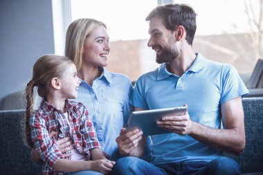 Güzel anne ve sevimli küçük kızları dijital tablet kullanma ve birlikte vakit ise gülümseyen