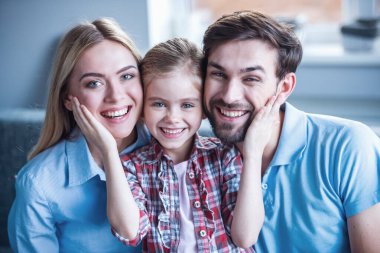 Güzel anne ve onların sevimli küçük kızını sarılma ve gülümseyerek kameraya bakarak portre