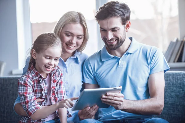 Güzel anne ve sevimli küçük kızları dijital tablet kullanma ve birlikte vakit ise gülümseyen