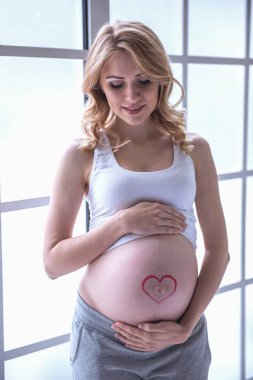 Güzel hamile kadının karnı sarılma ve gülümseyen