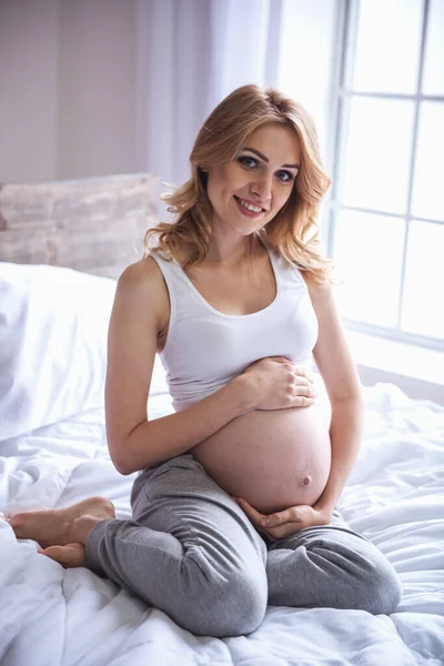 Hermosa Mujer Embarazada Está Tocando Barriga Mirando Cámara Sonriendo Mientras — Foto de Stock