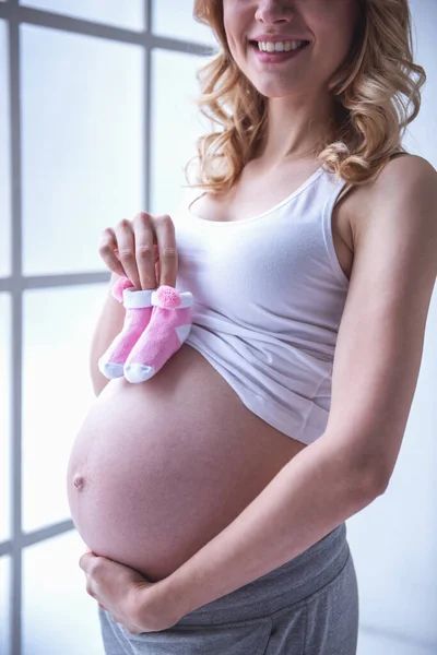 Güzel Hamile Kadının Karnı Bebek Patiği Tutarak Gülümseyen Dokunuyor — Stok fotoğraf