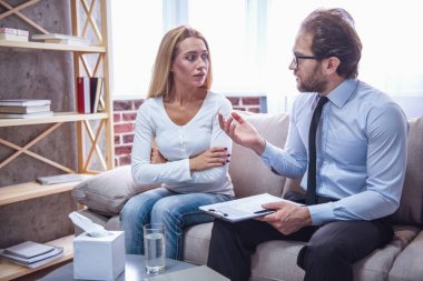 Psikolog. Güzel genç kadın kanepede oturan ve doktor konuşurken dinlerken