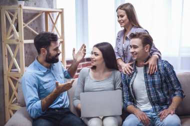 Gençler konuşuyor ve birlikte evde vakit ise gülümseyen bir dizüstü bilgisayar kullanıyorsanız