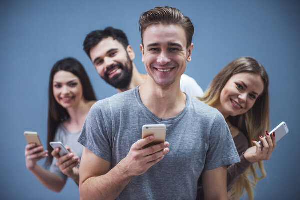 Bei Giovani Utilizzano Smartphone Sorridenti Sfondo Grigio — Foto Stock