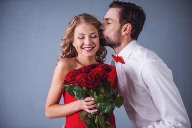 Zarif yakışıklı olan klasik gömlek Kırmızı papyon ile onun güzel kız arkadaşı gül veren ve onu öpüyor