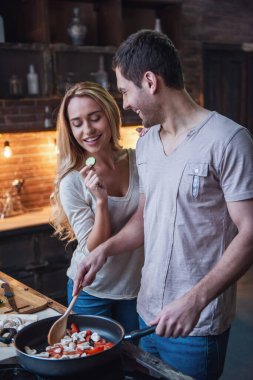 Güzel genç çift birlikte evde mutfakta yemek yaparken gülümsüyor