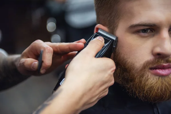 stock image Cropped image of handsome bearded man getting haircut by hairdresser at the barbershop