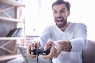 Yakışıklı genç adam evde kanepede otururken oyun konsolu oynuyor