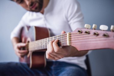Yakışıklı genç adamın gitar, gri arka plan üzerinde Resim kırpılmış