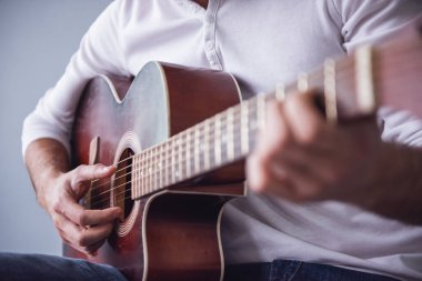 Yakışıklı genç adamın gitar, gri arka plan üzerinde Resim kırpılmış