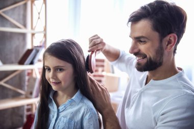 Yakışıklı genç baba küçük kızı penye ve süre onlar birlikte evde zaman geçiriyorsunuz gülümseyen