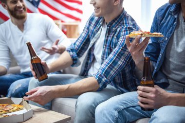 Çekici çocuklar bira içme, pizza yemek, söz ve evde istirahat ederken gülümseyen