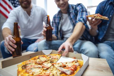 Çekici çocuklar bira içme, pizza yemek, söz ve evde istirahat ederken gülümseyen