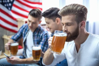 Çekici çocuklar bira içmek, konuşmak ve evde istirahat ederken gülümseyen