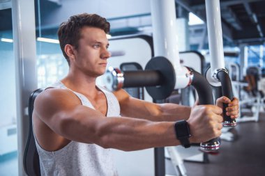 Kaslı yakışıklı genç bir fitness istasyonu, spor salonunda demir pompalama işe yarıyor mu