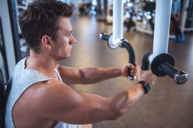 Kaslı yakışıklı genç bir fitness istasyonu, spor salonunda demir pompalama işe yarıyor mu