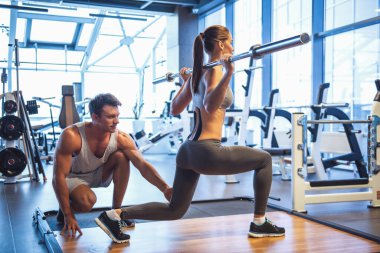 Çekici genç kadın halter salonunda çalıştığını, yakışıklı kaslı eğitmen ona yardım ediyor