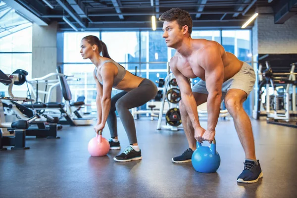 Çekici genç spor insanların kettlebell içinde jimnastik salonu ile çalışıyoruz