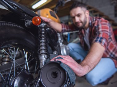 Yakışıklı adam bir motosiklet tamircisi temizlerken bez kullanarak