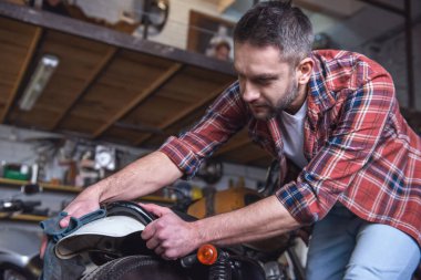 Yakışıklı adam bir motosiklet tamircisi temizlerken bez kullanarak