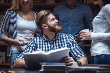 Genç akıllı insanlar konuşmak ve modern kütüphanede okurken gülümseyen