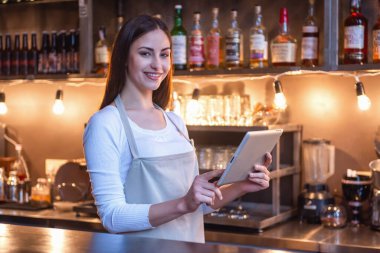 Güzel kadın barista dijital tablet kullanma ve barda duran gülümseyen Cafe counter