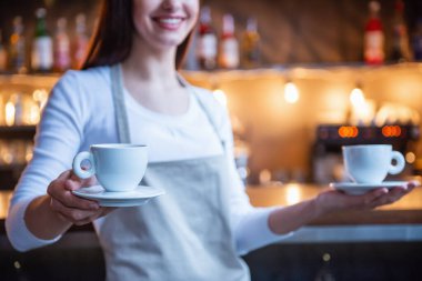 Güzel kadın barista kırpılmış görüntü bir bardak tutan ve bar yakınındaki dururken gülümseyen kafede karşı