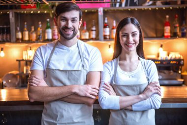 Güzel genç garson kameraya bakarak ve barda duran gülümseyen Cafe counter