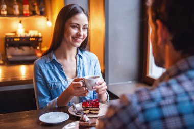 Mutlu genç çift kahve içme, konuşma ve kafede otururken gülümseyen