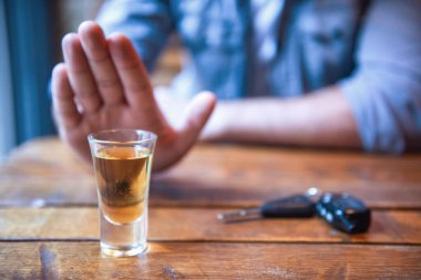 Do not drink and drive! Cropped image of man showing stop gesture and refusing to drink. Car keys lying near clipart