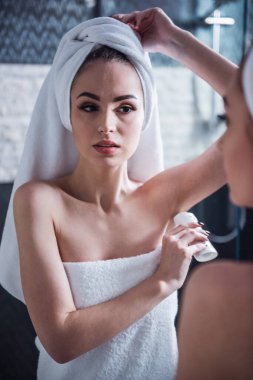 Banyo havlusu güzel kız onun koltukaltı içine banyo aynaya bakarken deodorant uyguluyor
